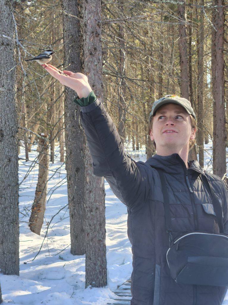 A photo of me (Connor) holding a Black-capped Chickadee.